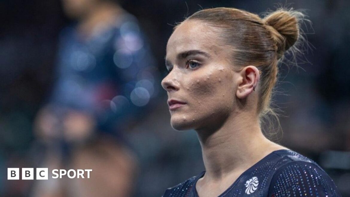 Alice Kinsella does a split leap on beam